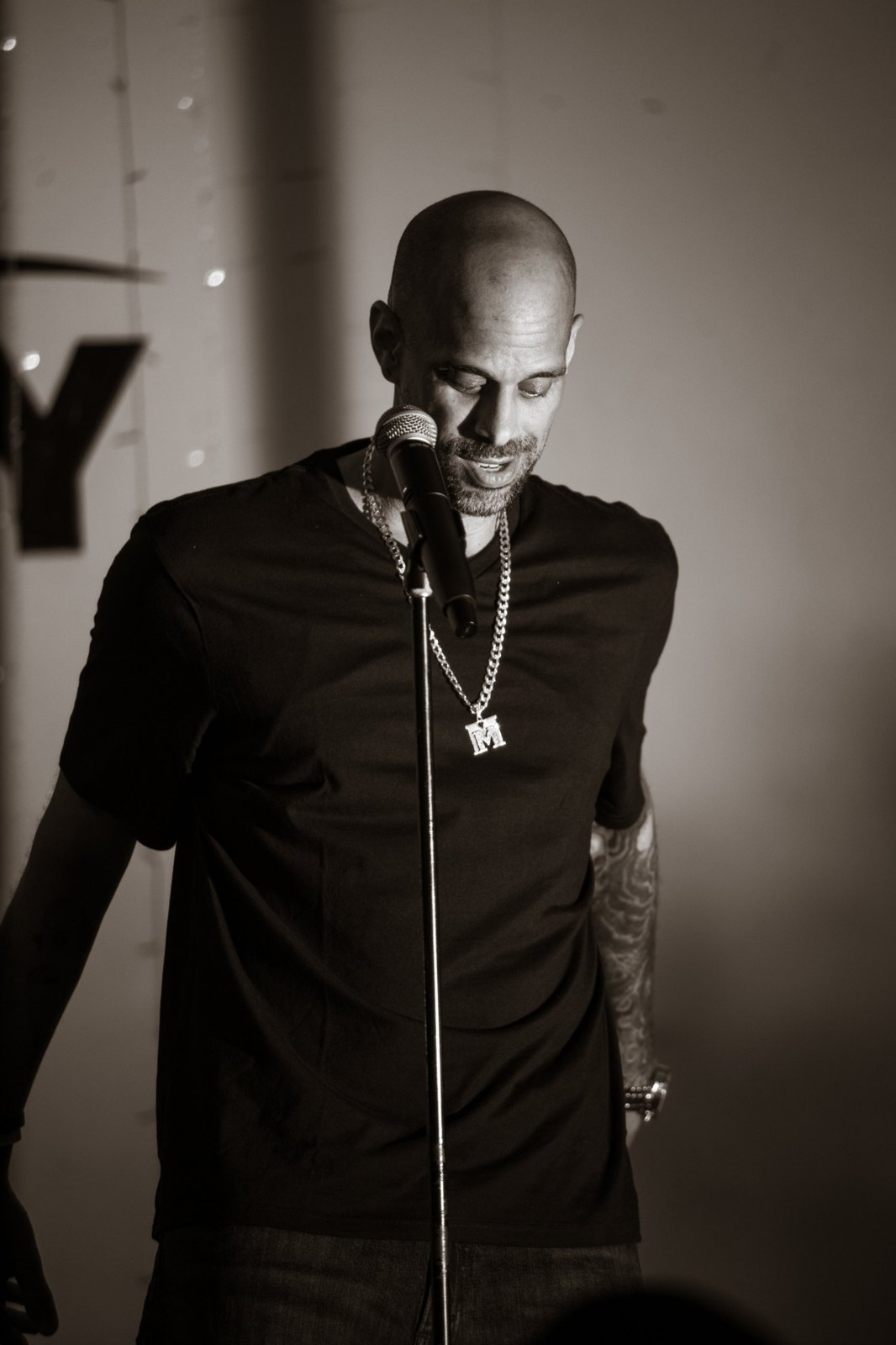 Marc Marcel performing at a microphone stand, head bowed